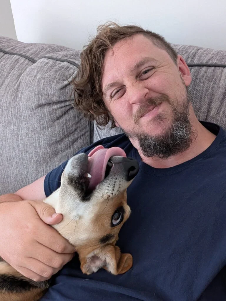 Dog owner cuddling with happy dog on the couch, showing a safe and loving environment during Halloween season, from Doggy Doods in St. Charles County