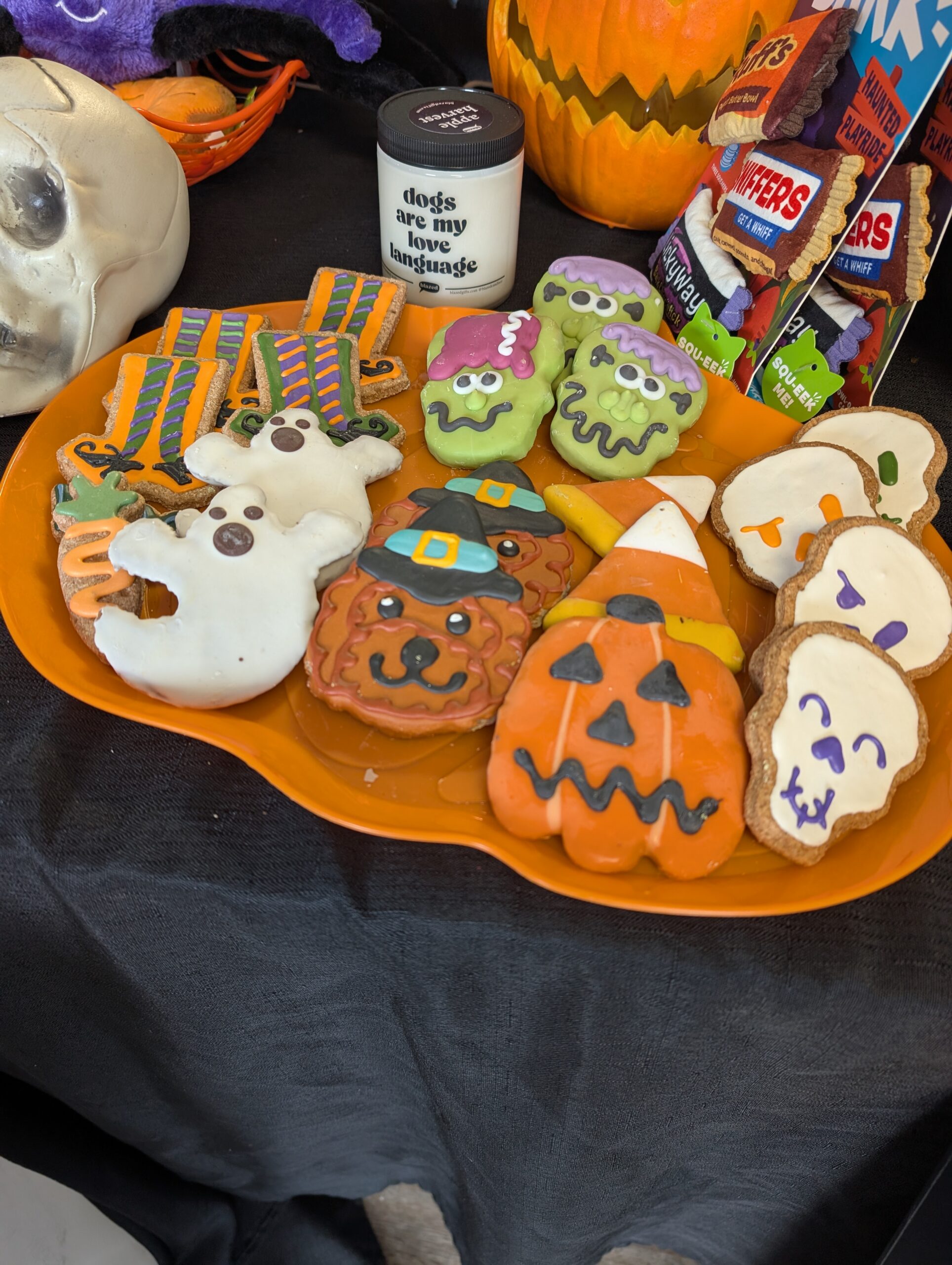 Festive Halloween-themed dog treats from Yadi's Yummies in St. Peters, Missouri, displayed on an orange tray with pumpkins and dog toys.