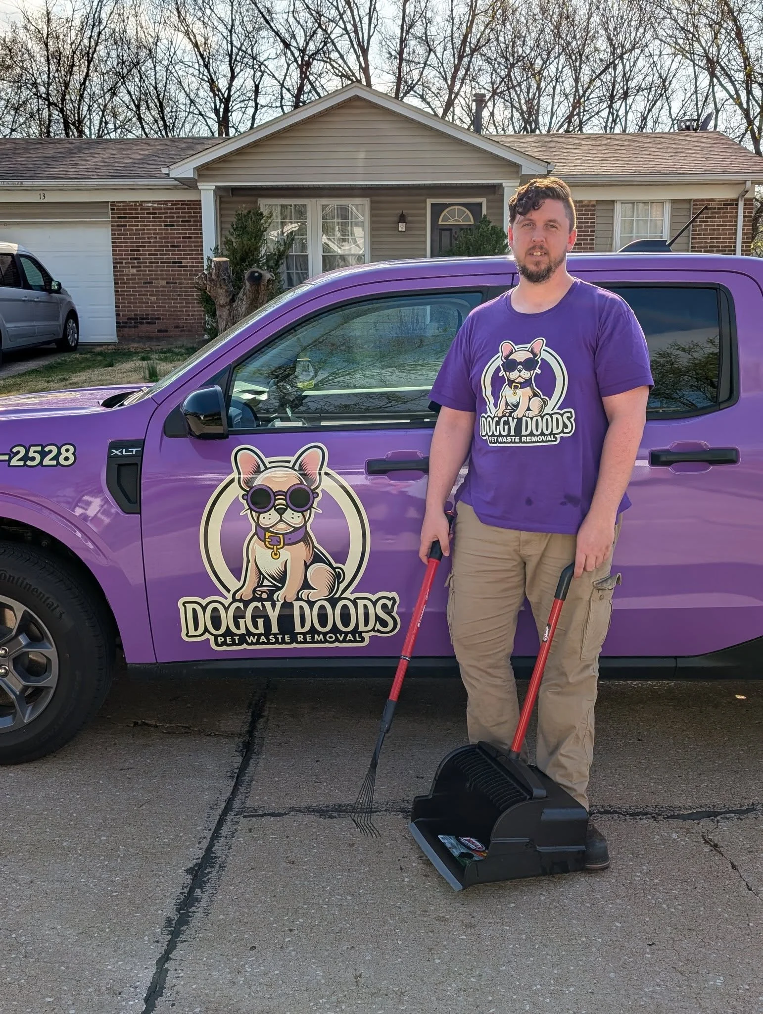 Doggy Doods owner standing next to the company's purple truck and pooper scooper equipment in St. Charles County, Missouri.